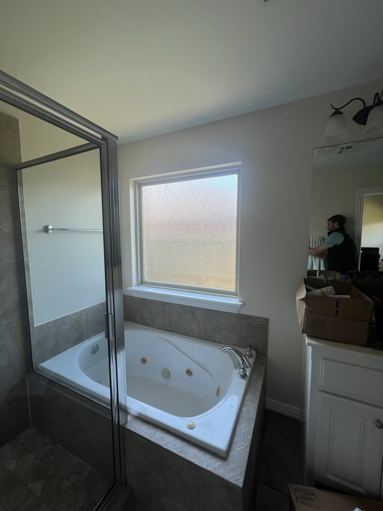 Before: a jetted corner tub and a separate framed glass shower in the main bathroom