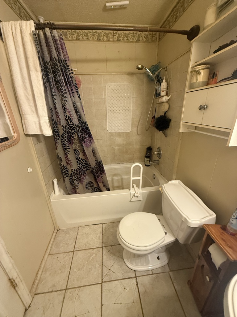 Before: a tub and shower combination with a curtain and a clamp on tub rail