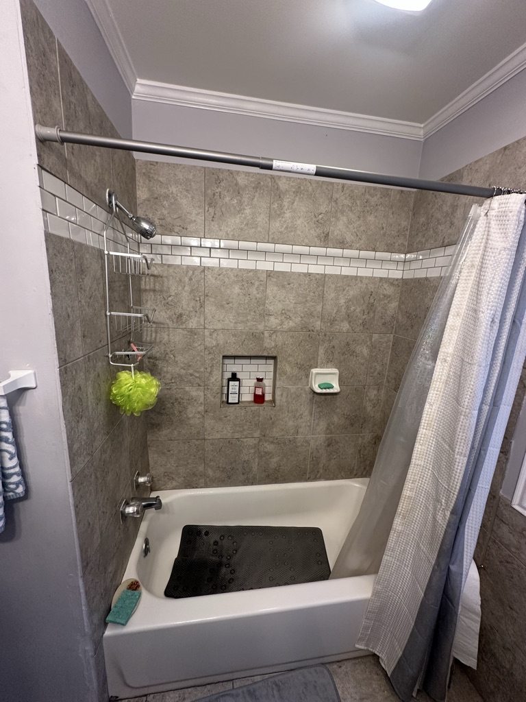 Before: an old tub and shower combination with a shower curtain
