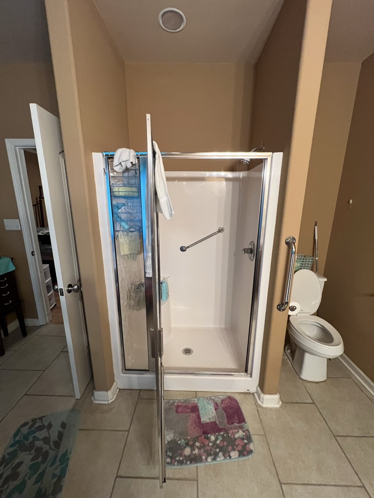 Before: a worn fiberglass shower stall with a hinged glass door