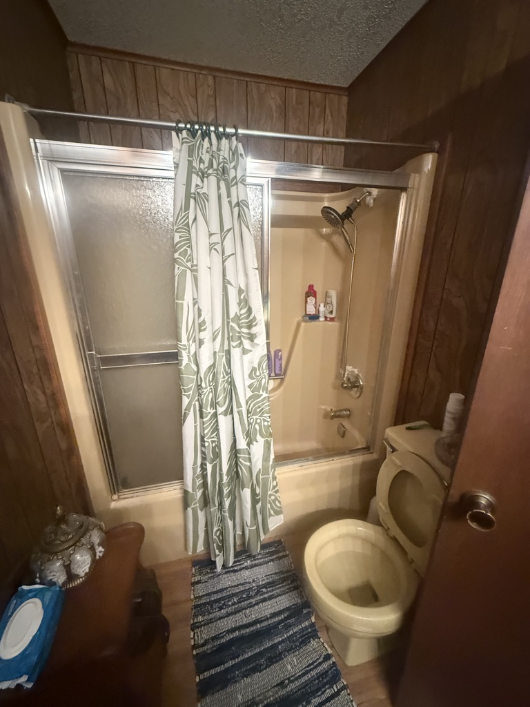 Before: a tub and shower combination with a frosted glass enclosure and a curtain