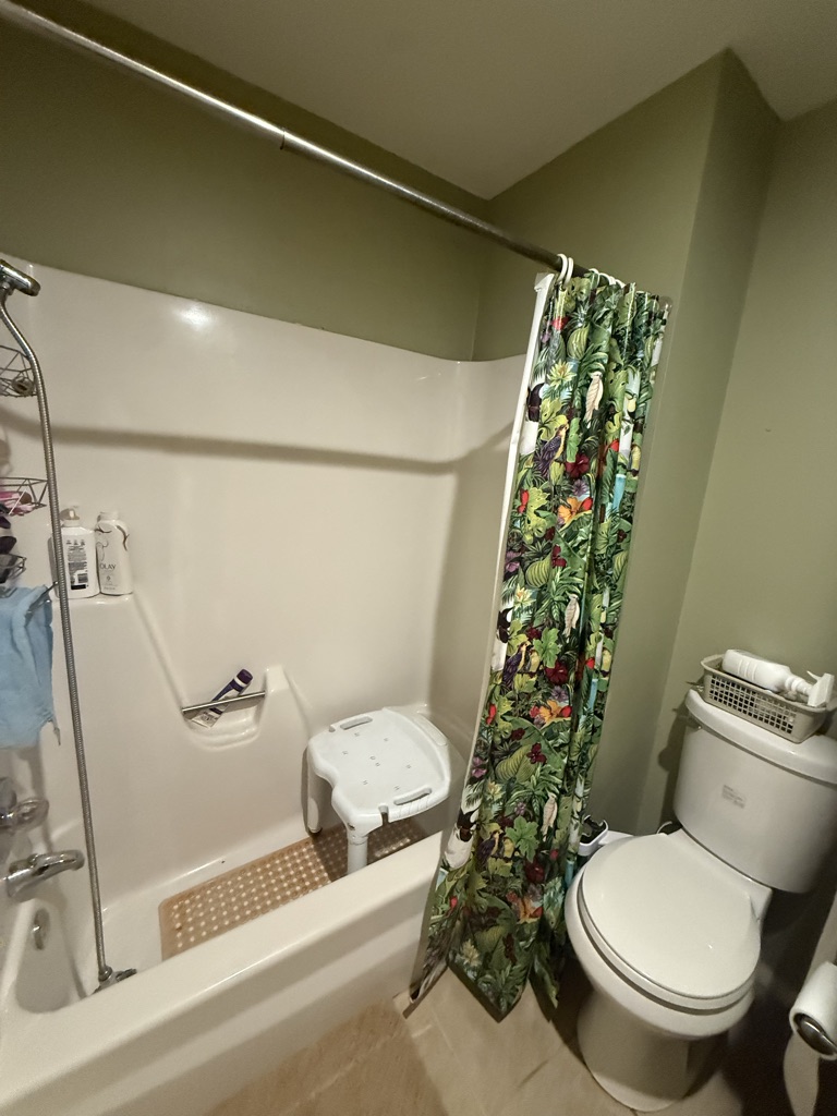 Before: a fiberglass tub and shower combination with a shower chair