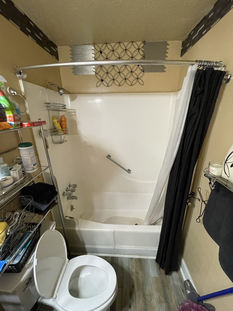 Before: a fiberglass tub and shower combination with a curtain