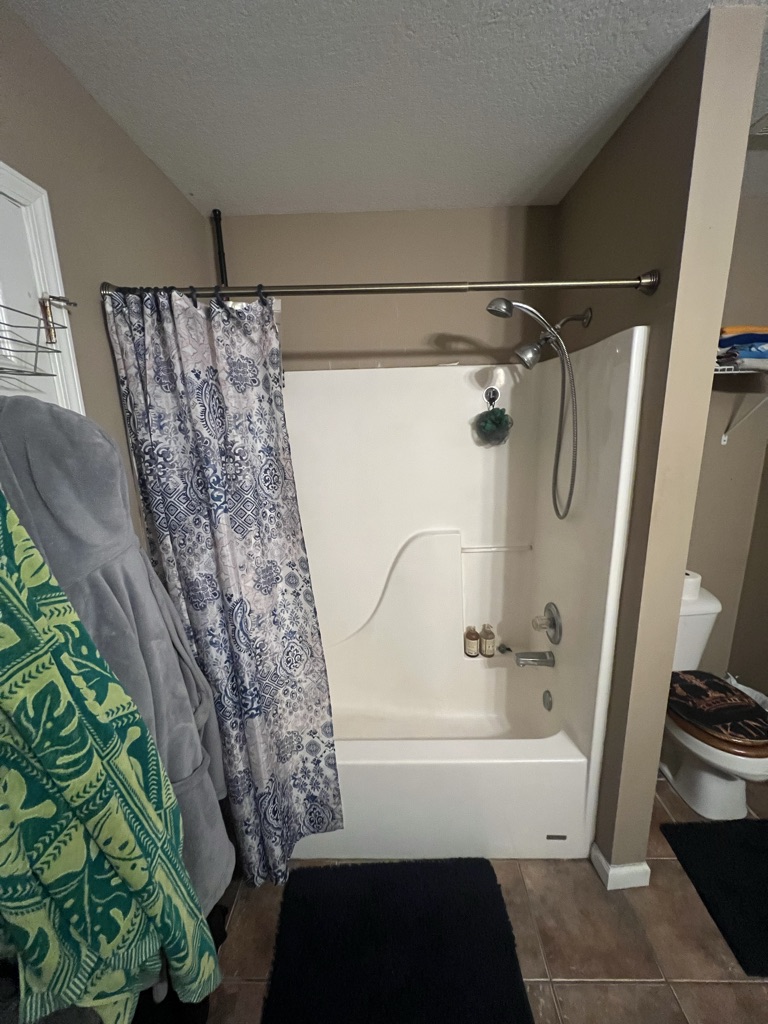 Before: a fiberglass tub and shower combination with a curtain