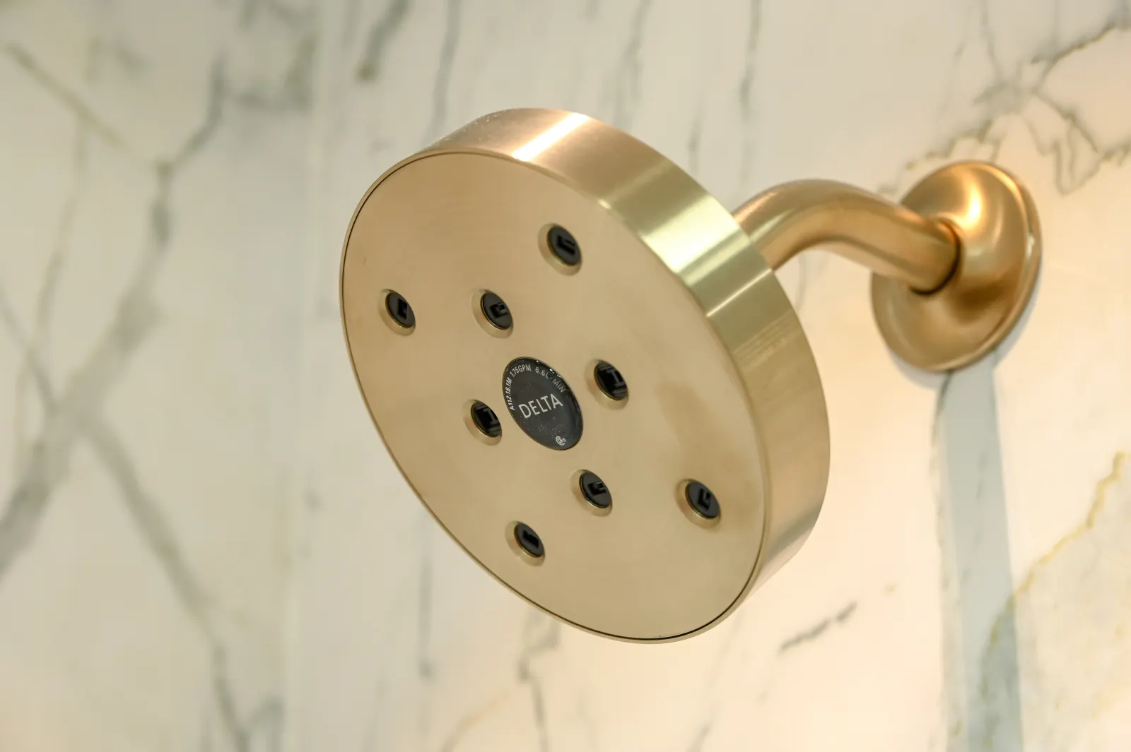 Brushed gold shower head on marble look wall