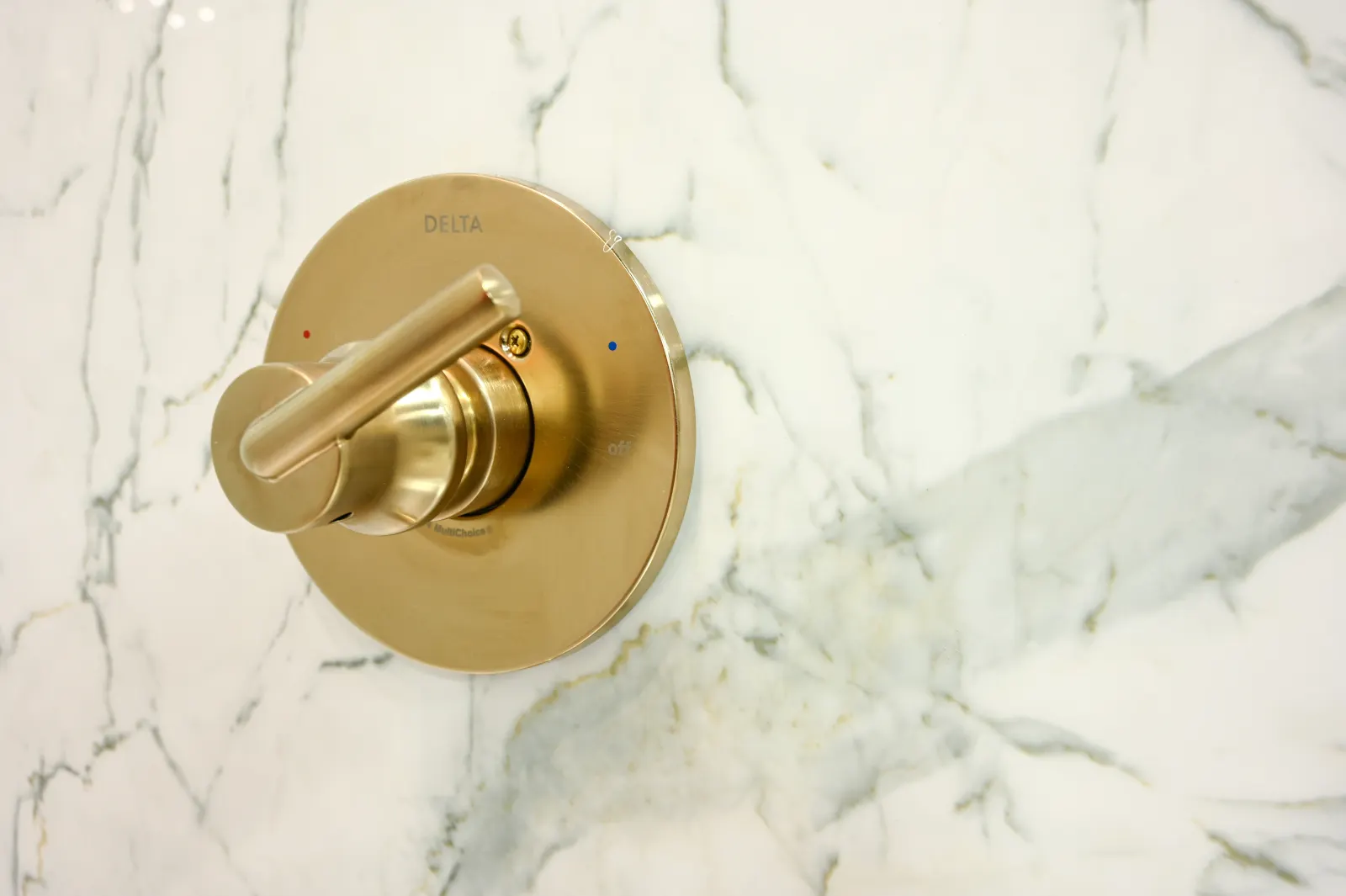 Brushed gold shower valve trim on marble look wall