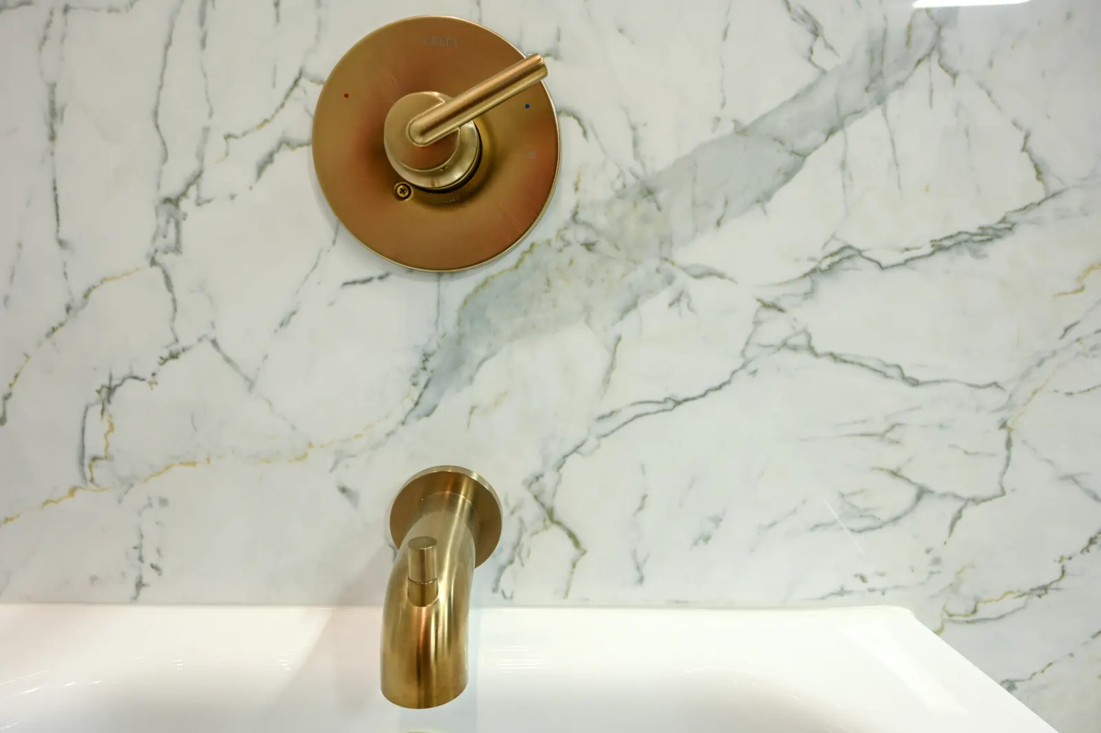 Brushed gold tub spout and handle, marble look wall