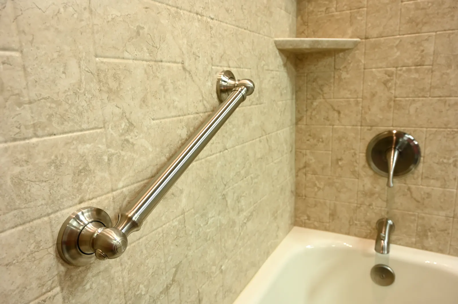 Brushed nickel grab bar on tan wall over tub