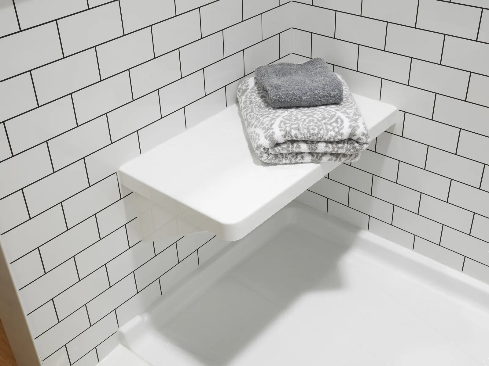 Corner shower seat and bench with towels on subway pattern