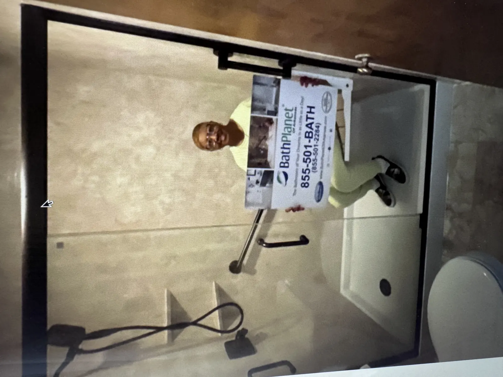 Customer seated in new shower with sign