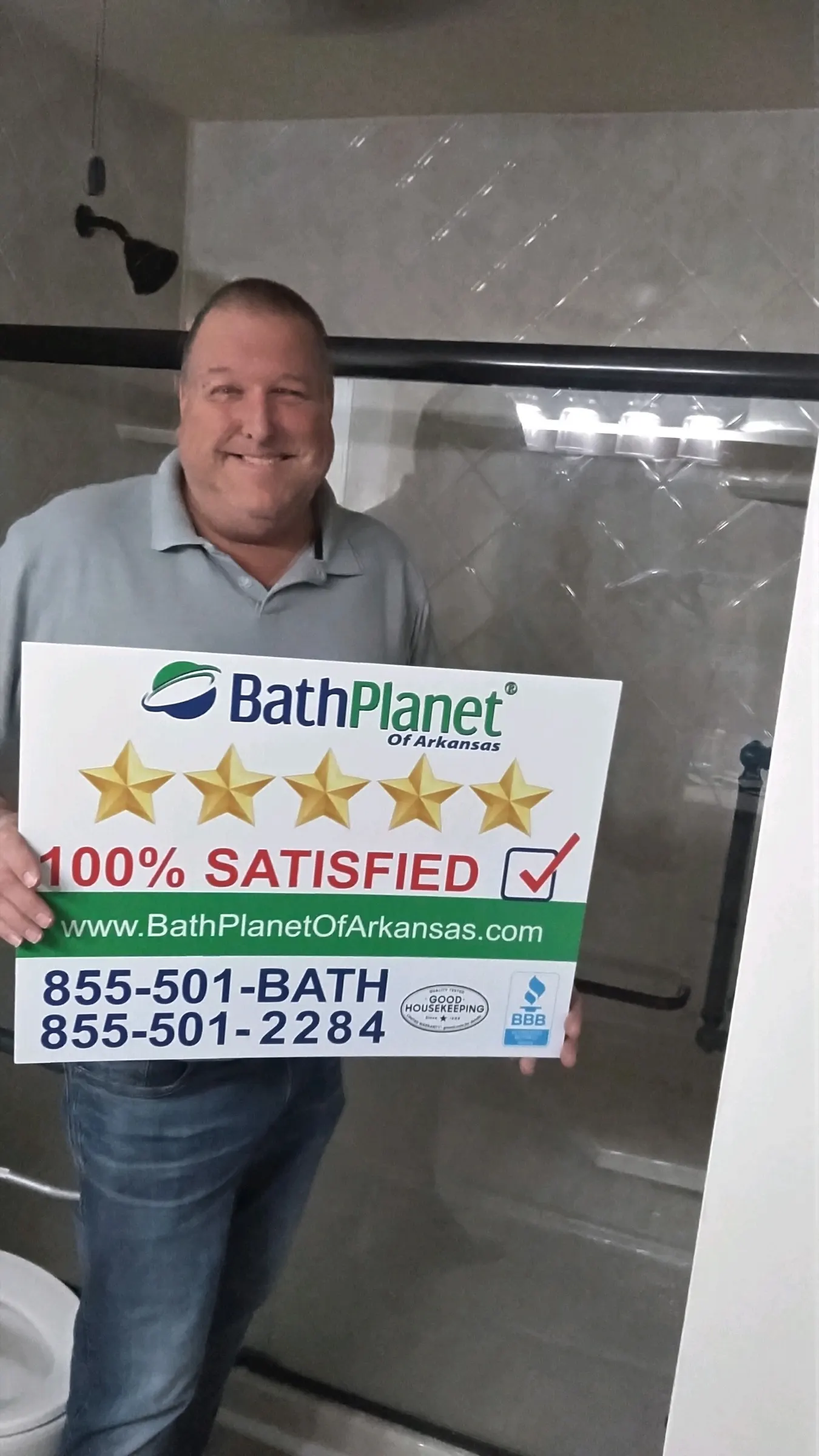 Homeowner holding a 100% Satisfied sign in front of his new shower