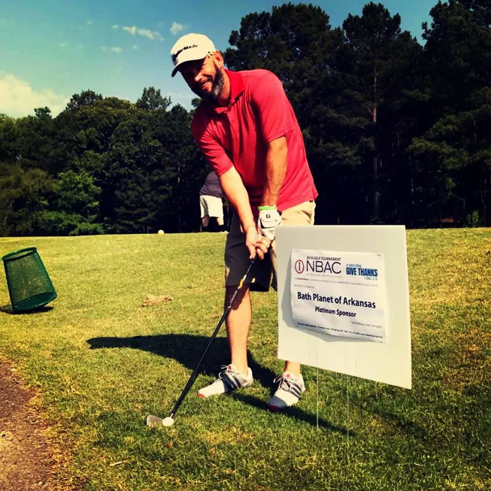 Man golfing with NBAC sign