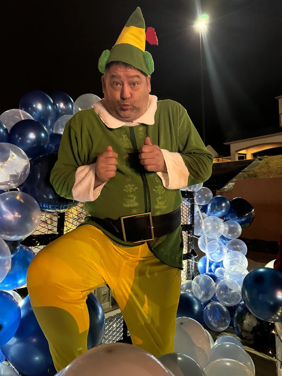 Man in elf costume with balloons on Christmas parade float
