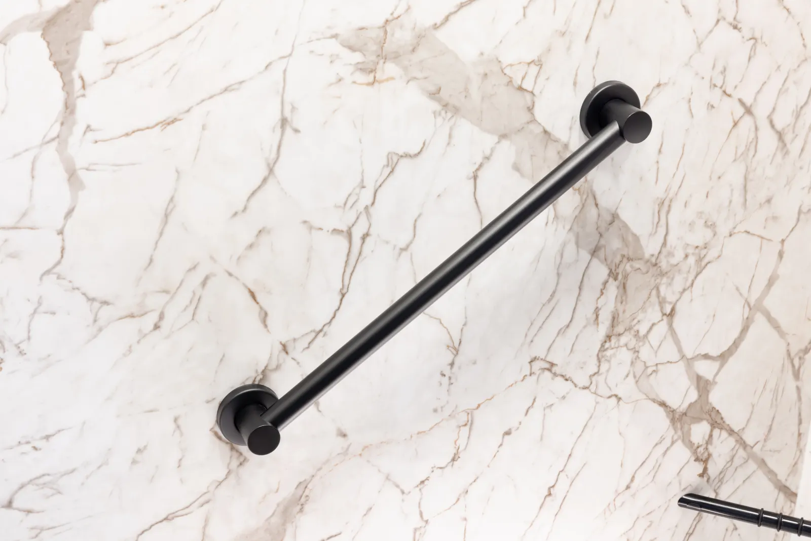 Matte black towel bar on white marble look wall