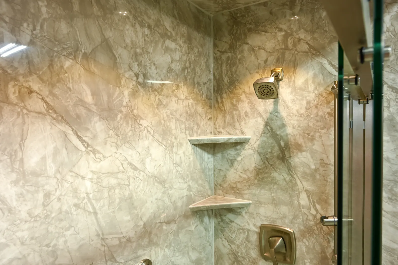 Tan marble look shower wall, corner shelves, glass door