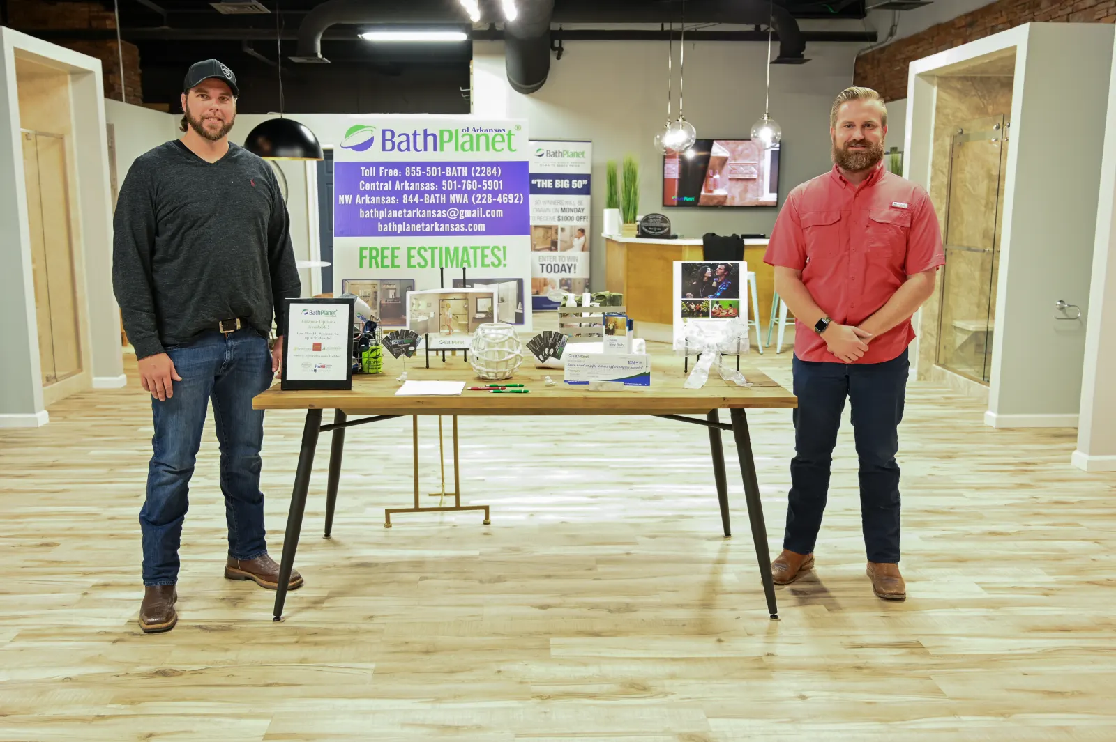 Two members of the Bath Planet of Arkansas team at the showroom holding an award